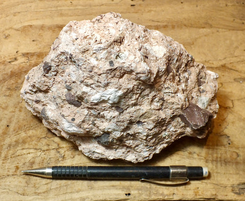 tuff breccia - display specimen of a spectacular tuff breccia with a variety of clast types embedded in the pinkish ash
